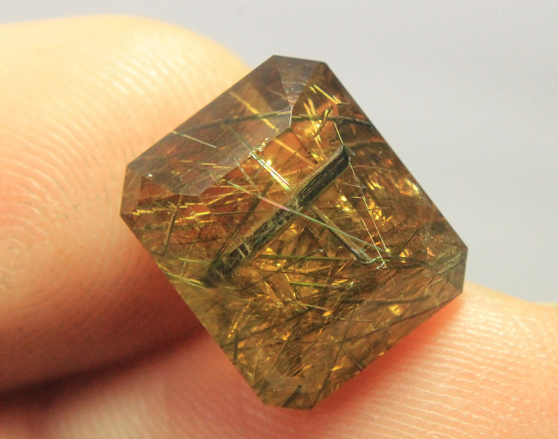 golden danburite gemstone with rutile inclusions faceted